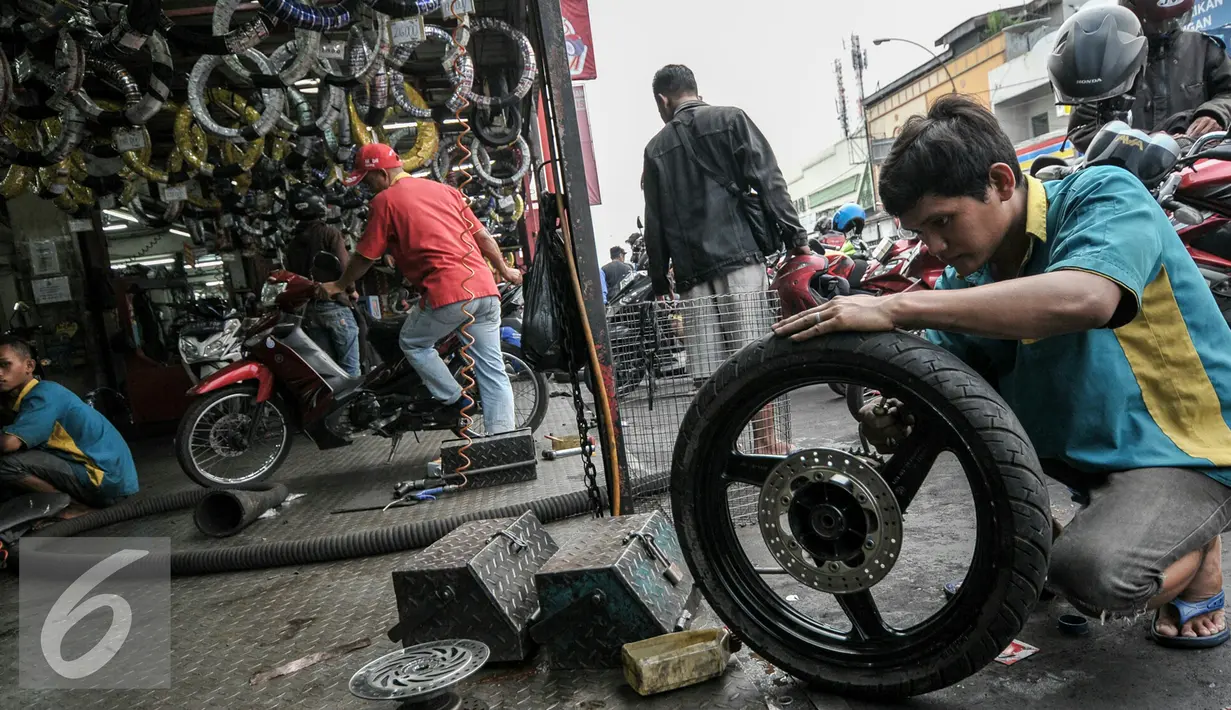 Montir sedang memperbaiki roda sepeda motor di bengkel kawasan Pasar Minggu, Jakarta, Kamis (30/6). Jelang Lebaran, pemudik motor mulai serbu jasa servis bengkel motor untuk persiapan mudik. (Liputan6.com/Yoppy Renato)