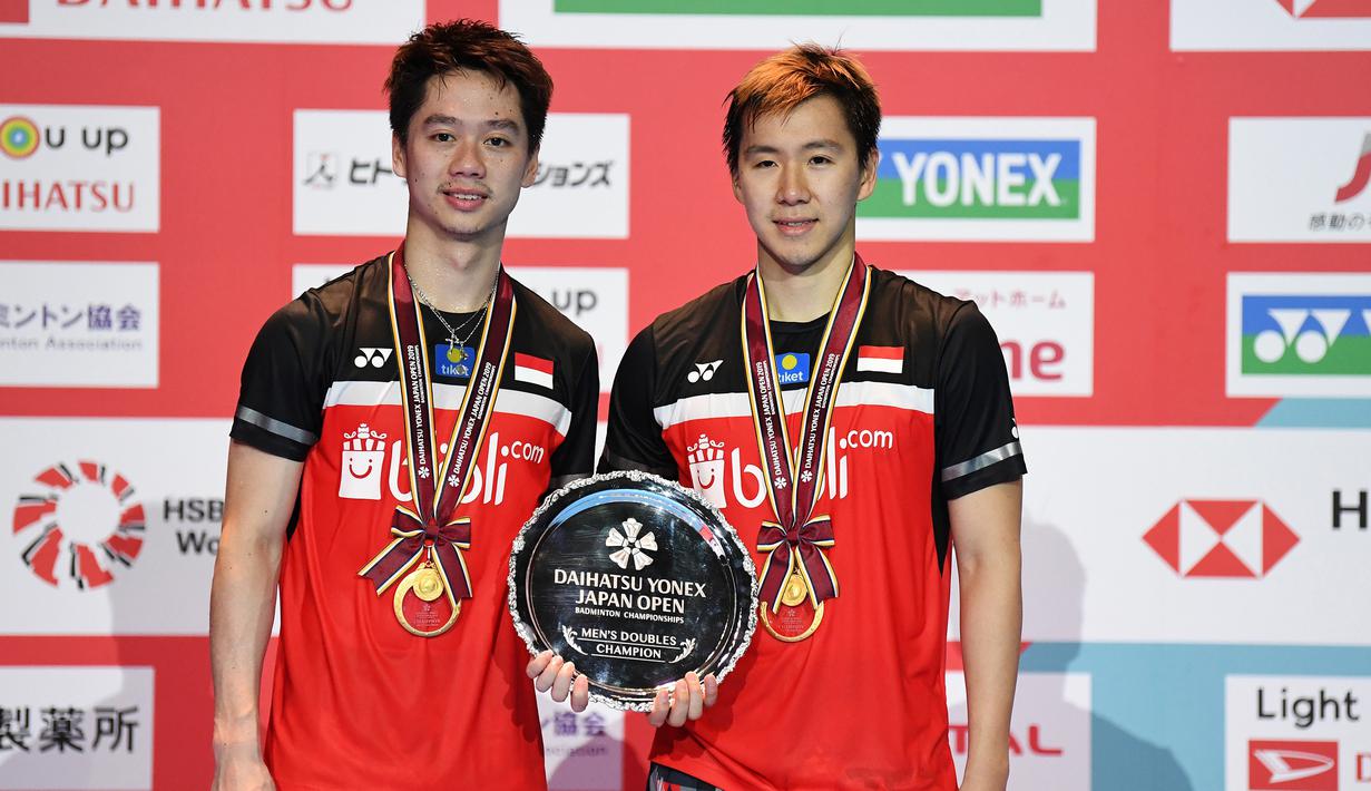 Ganda putra Kevin Sanjaya/Marcus Fernaldi Gideon berpose dengan trofi usai bertanding melawan  Hendra Setiawan / Mohammad Ahsan pada babak fina Jepang Terbuka 2019 di Tokyo (28/7/2019). Kevin / Marcus menang  21-19 dan 23-21.  (AFP Photo/Charly Triballeau)