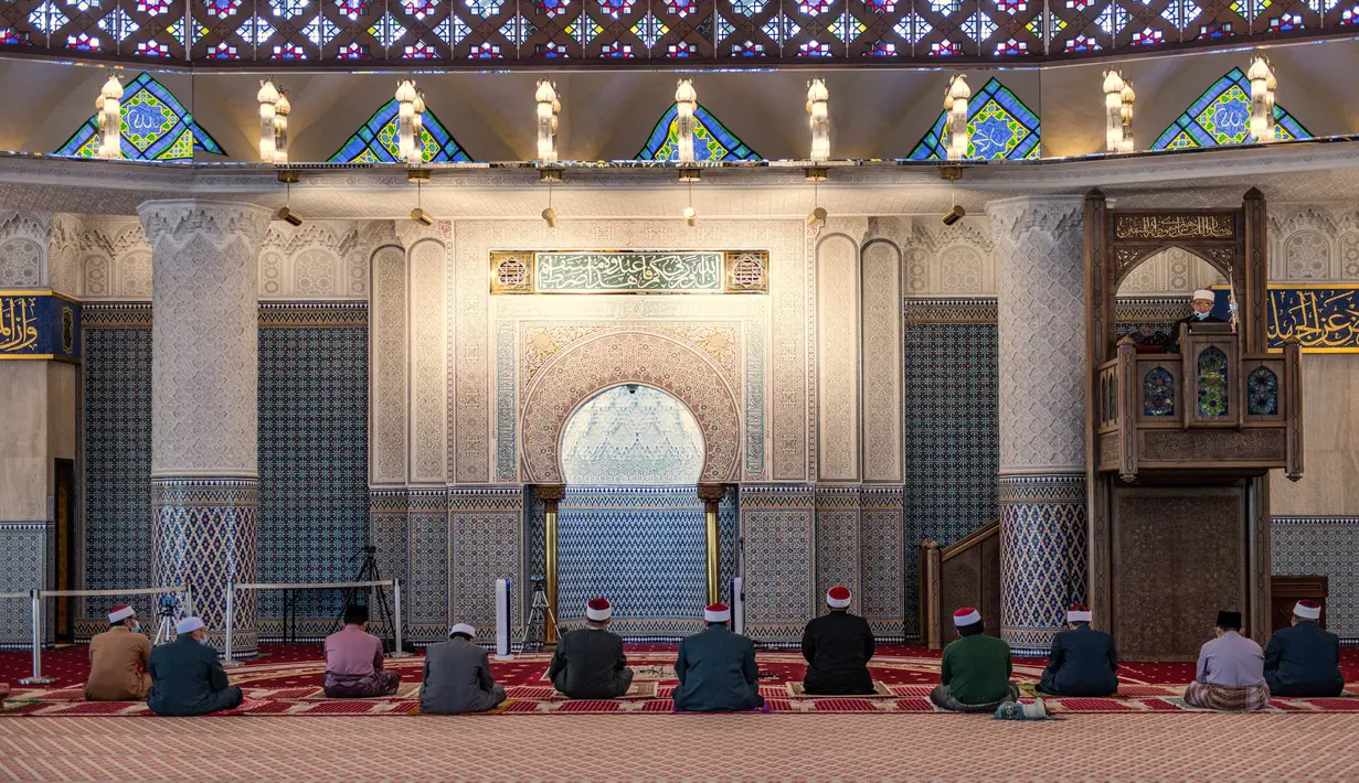 Petugas masjid mendengarkan khotbah salat Jumat dengan menerapkan jaga jarak aman saat Ramadan di Masjid Negara Malaysia, Kuala Lumpur, Malaysia, Jumat (15/5/2020). Masjid Negara Malaysia kembali dibuka setelah pemerintah setempat melonggarkan lockdown akibat pandemi COVID-19. (Mohd RASFAN/AFP)