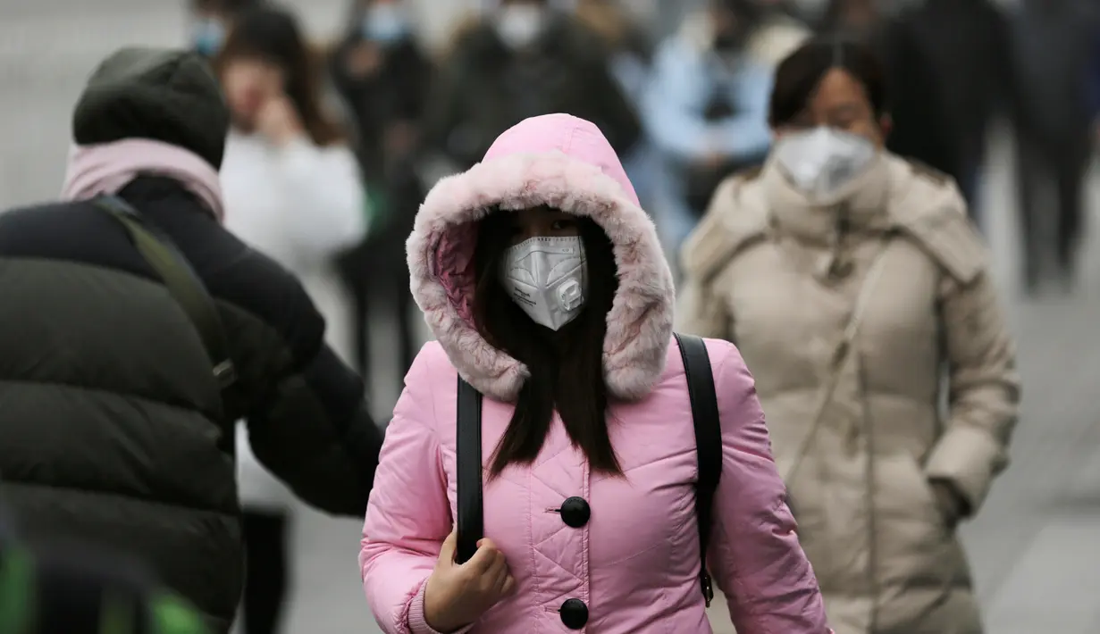 Seorang warga mengenakan masker ketika beraktivitas di distrik pusat bisnis Beijing, Tiongkok (21/12). Diberitahukan sejumlah anak-anak di beberapa kota di China seperti Beijing, Shanghai dan Hong Kong terkena masalah pernapasan. (Reuters/Jason Lee)