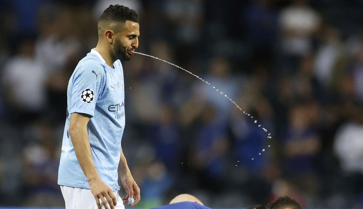Penyerang Manchester City, Riyad Mahrez, menyemburkan air saat melawan Chelsea pada laga final Liga Champions di Stadion Dragao, Minggu (30/5/2021).  Chelsea menang dengan skor 1-0. (Carl Recine/Pool via AP)