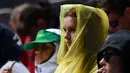 Seorang wanita memakai jas hujan menyaksikan pertandingan tunggal tunggal pria antara petenis Italia Andreas Seppi dan petenis Prancis Corentin Moutet pada hari pertama turnamen tenis Australia Terbuka di Melbourne (15/1). (AFP Photo/Saeed Khan)