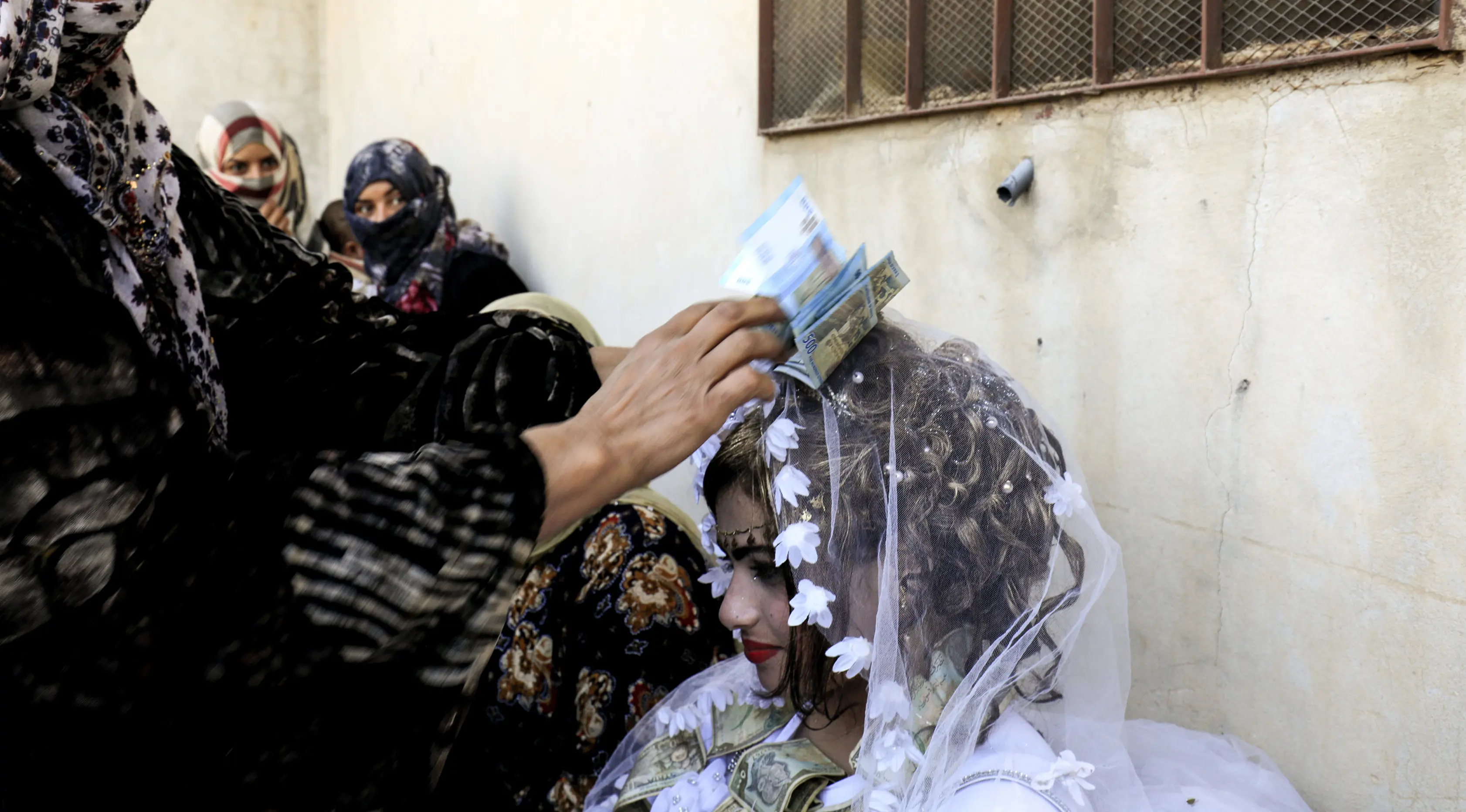 Seorang wanita menaruh uang di kepala pengantin wanita, Heba saat prosesi pernikahan di Raqqa, Suriah (27/10). Heba dan Ahmed merupakan pasangan pertama yang menikah usai Kota Raqqa jatuh dari tangan ISIS. (AFP Photo/Delil Souleiman)