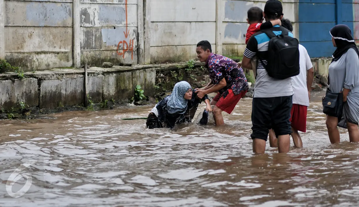 Wanita yang terperosok dalam lubang ditolong oleh warga yang kebetulan melintas di kawasan Bukit Duri saat dilanda banjir, Jakarta, Selasa (21/2). (Liputan6.com/Yoppy Renato)