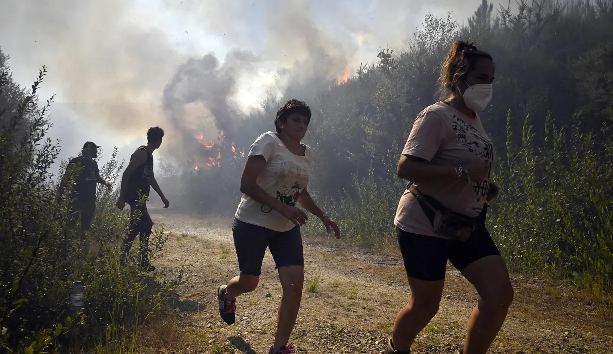 Orang-orang berlari untuk menyelamatkan diri dari api kebakaran hutan di dekat desa Melon, Spanyol barat laut, pada 17 Agustus 2025. (MIGUEL RIOPA/AFP)
