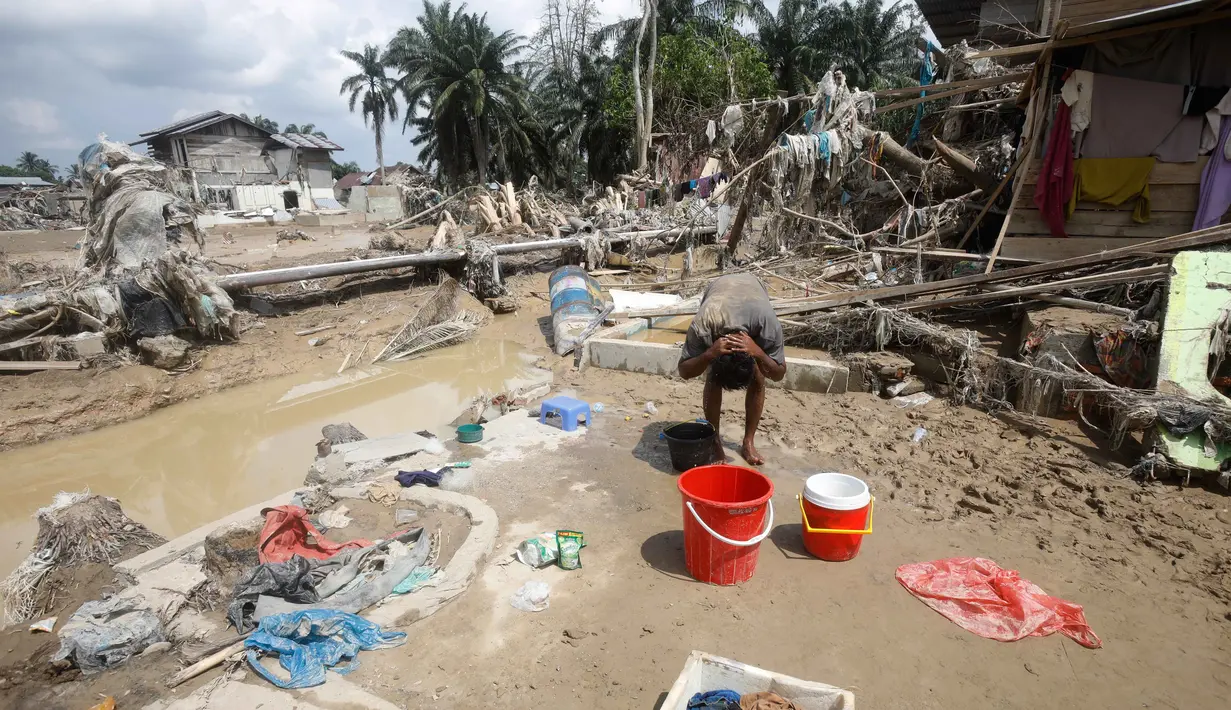 Seisi kota nyaris mati. Tidak ada listrik, air bersih, apalagi jaringan telekomunikasi. Warga seperti terperangkap. Tampak dalam foto, seorang korban selamat membersihkan diri di area yang terdampak banjir bandang di Aceh Tamiang, Sumatra, Jumat 5 Desember 2025. (AP Photo/Binsar Bakkara)