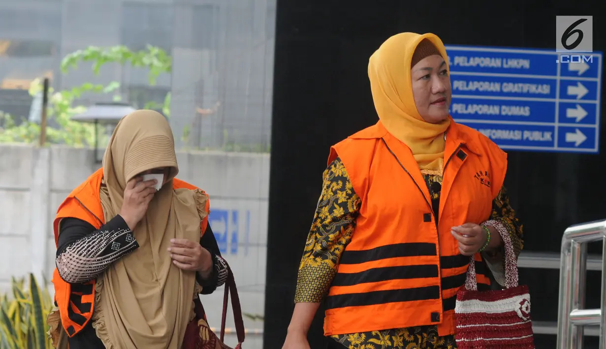Tersangka Anggota DPRD Kota Malang Asia Iriani (kanan) dan Een Ambarsari (tengah) tiba di Gedung KPK, Jakarta, Rabu (21/11). Keduanya banyak menunduk saat tiba di Gedung KPK. (Merdeka.com/Dwi Narwoko)