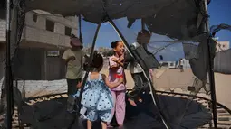 Anak-anak pengungsi Palestina bermain trampolin di sebuah kamp tenda selama Hari Raya Idul Adha di Khan Younis, Jalur Gaza, Rabu 27 Mei 2026. (AP Photo/Abdel Kareem Hana)