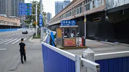 Seorang pria berjalan di samping Pasar Grosir Makanan Laut Huanan yang masih tutup di Wuhan, Provinsi Hubei, China, 4 Agustus 2020. Wuhan kembali pulih sejak karantina terkait COVID-19 dicabut. (Hector Retamal/AFP)