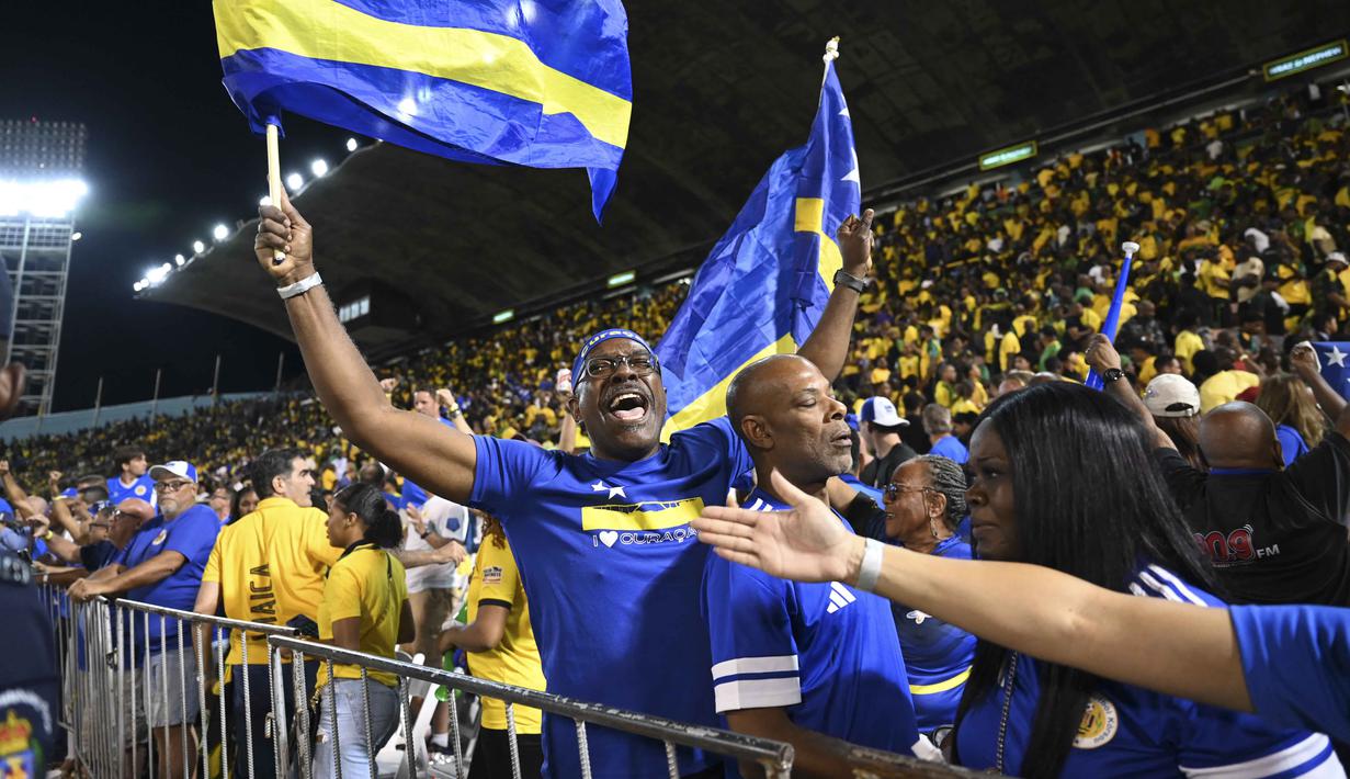 Hasil imbang tersebut mengukuhkan performa konsisten Curacao di Grup B Kualifikasi Piala Dunia 2026 zona CONCACAF yang sebelumnya mencatat tiga kemenangan dan tiga hasil imbang tanpa kekalahan. Tampak dalam foto, suporter Timnas Curacao merayakan hasil imbang melawan Jamaika pada Grup B Kualifikasi Piala Dunia 2026 zona CONCACAF di Independence Park Stadium, Jamaika pada 18 November 2025. (Ricardo MAKYN/AFP)
