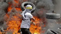 Pengunjuk rasa Palestina membakar ban di tengah bentrokan dengan pasukan keamanan Israel menyusul demonstrasi menentang perampasan tanah oleh Israel di Desa Kfar Qaddum dekat pemukiman Yahudi Kedumim, Tepi Barat, 6 Mei 2022. (JAAFAR ASHTIYEH/AFP)