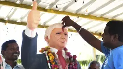 Bussa Krishna (33) memberikan tanda merah di dahi patung Presiden AS Donald Trump saat memanjatkan doa  di Desa Konney, Telangana, negara bagian India selatan (14/2/2020).  Trump dan istrinya Melania akan memulai kunjungan dua hari ke India. (AFP/Noah Seelam)