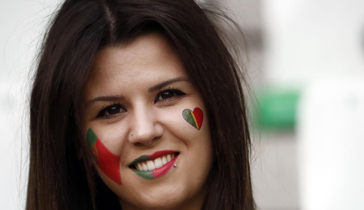 Suporter Portugal ini mengecat wajahnya dengan gambar bendera Portugal saat mendukung timnya melawan Islandia di Stadion Geoffroy-Guichard, Saint-Etienne, (14/10/2016). (AFP/Odd Andersen)