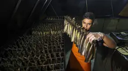 Seorang pemuda Palestina bekerja di fasilitas pengasapan makarel saat ikan itu akan dijual jelang liburan Idul Fitri di Rafah di Jalur Gaza selatan (26/4/2022). Ikan asap makarel menjadi salah satu menu hidangan buka puasa dan Idul Fitri terfavorit bagi warga Gaza selama Ramadhan.(AFP/Said Khatib)