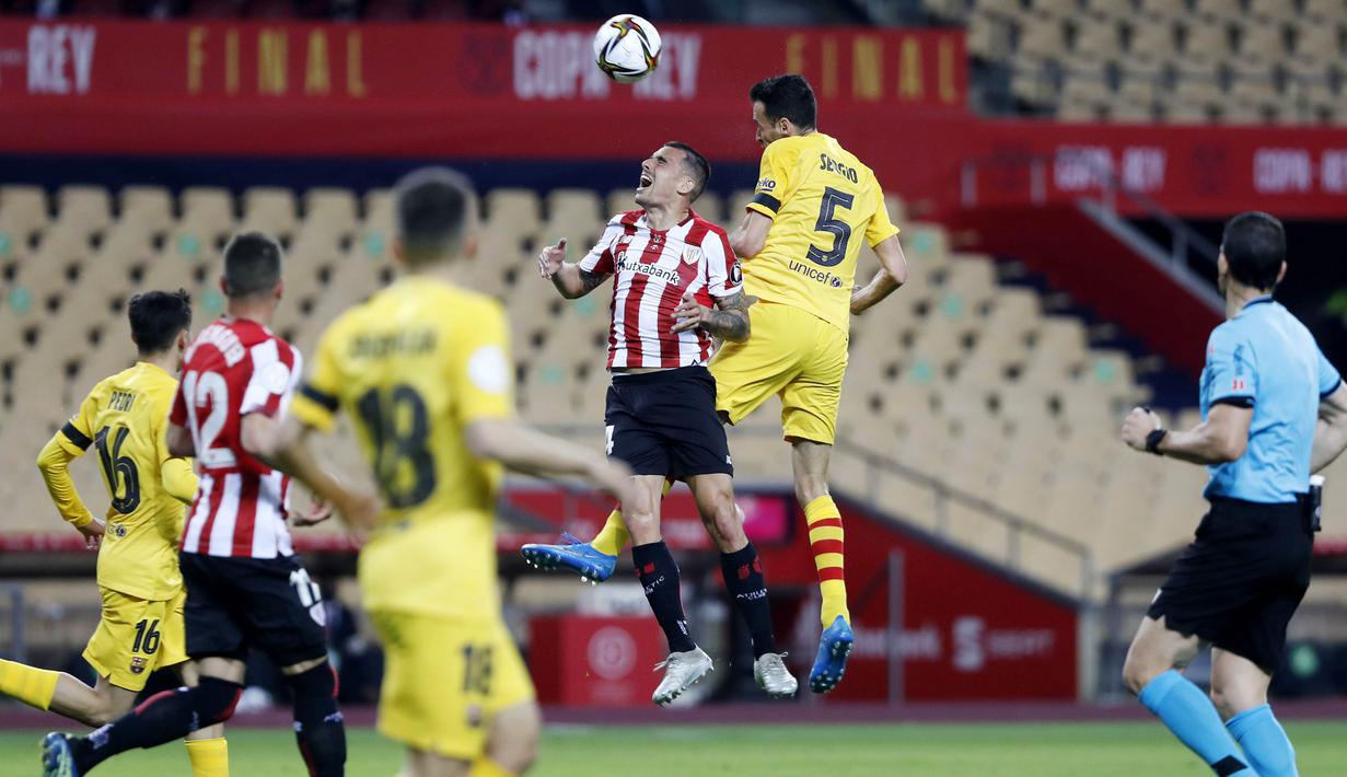 Pemain Barcelona, Sergio Busquets, duel udara dengan pemain Athletic Bilbao, Inigo Martinez, pada laga final Copa del Rey di Stadion Olimpico de Sevilla, Minggu (18/4/2021). Barcelona menang 4-0 atas Athletic Bilbao. (AFP/Cristina Quicler)