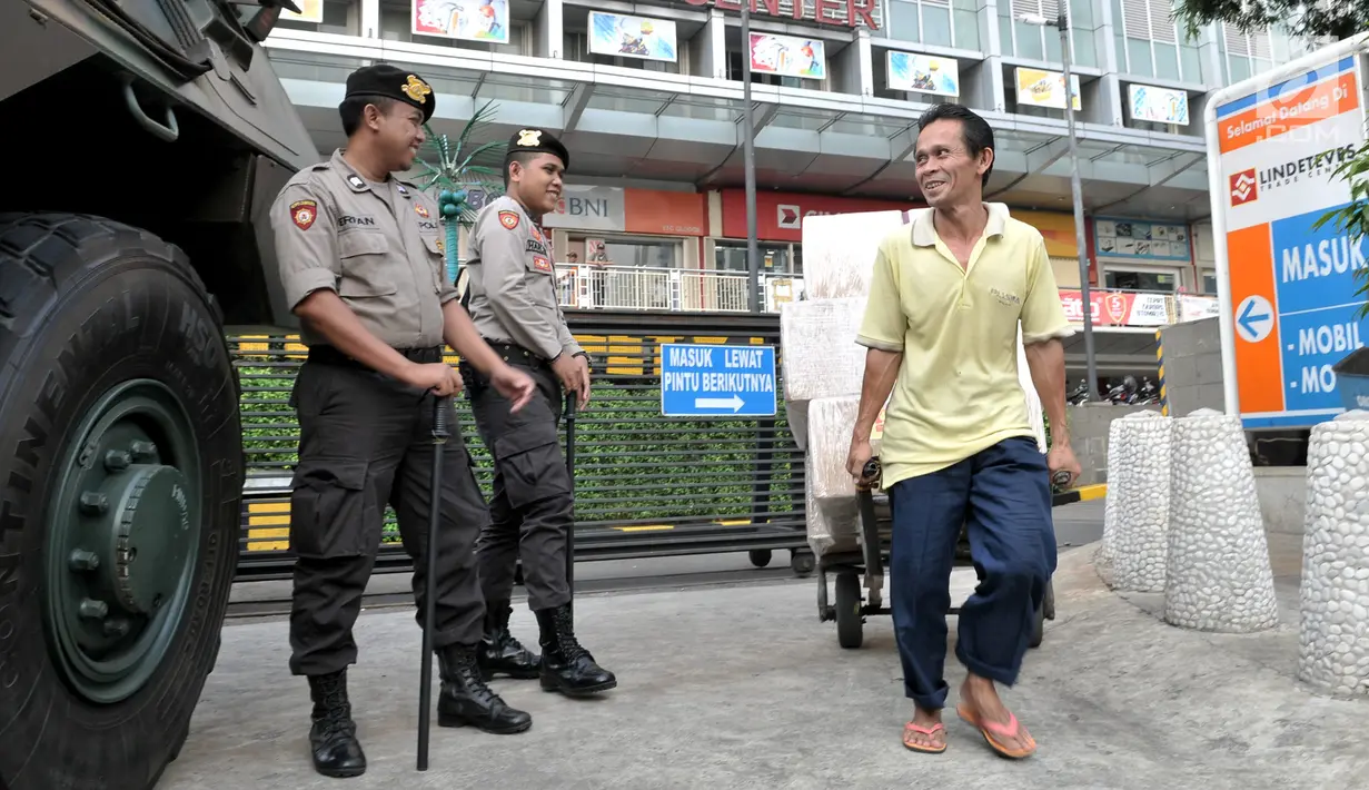 Warga melintasi Panser Anoa dan polisi yang berjaga di pusat perbelanjaan kawasan Glodok, Jakarta, Kamis (27/6/2019). TNI-Polri mengamankan sejumlah pusat perbelanjaan di Jakarta guna mengantisipasi hal tidak diinginkan saat pembacaan putusan sidang sengketa Pilpres 2019. (merdeka.com/Iqbal Nugroho)