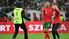 Seorang steward berlari untuk mengusir salah satu suporter yang masuk ke lapangan untuk berswafoto dengan pemain bintang, Cristiano Ronaldo selama pertandingan sepak bola UEFA Nations League 2024/2025, Liga A Grup A1 Polandia vs Portugal di Stadion PGE Narodowy, Warsawa, Polandia pada Sabtu 12 Oktober 2024 atau Minggu (13/10/2024) dini hari WIB. (Sergei GAPON/AFP)
