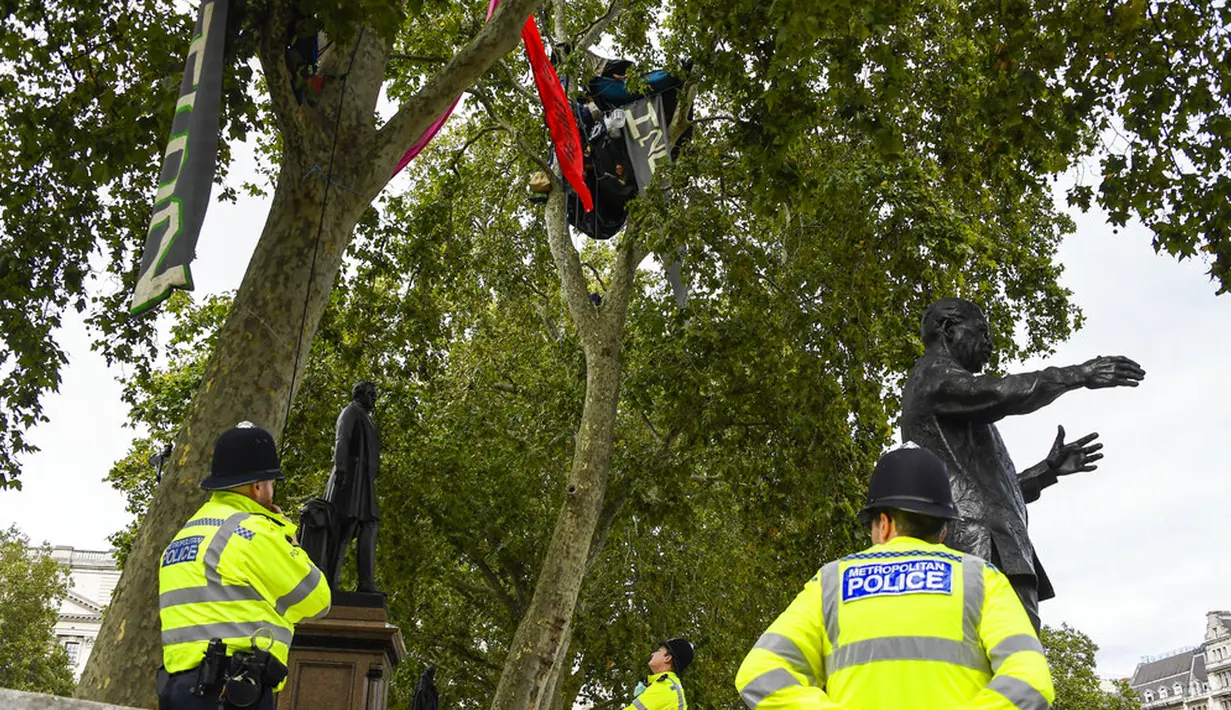 Polisi berpatroli saat aktivis Extinction Rebellion menaiki dua pohon di Parliament Square sebagai bagian dari protes perubahan iklim di London, Inggris, Selasa (8/9/2020). Menggelar aksi di tengah pandemi COVID-19, para aktivis mengenakan masker selama protes berlangsung. (AP Photo/Alberto Pezzali)