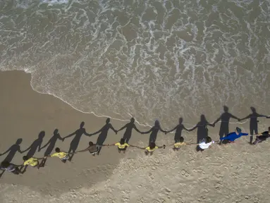 Orang-orang membuat barisan berpegangan tangan di sepanjang pantai Sao Conrado untuk berpelukan secara simbolis dengan laut pada Hari Laut Sedunia di Rio de Janeiro, Brasil, Kamis, 8 Juni 2023. (AP Photo/Bruna Prado)