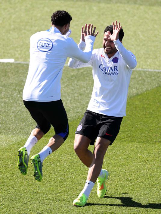 Kala itu, PSG berhasil menyingkirkan Liverpool melalui drama adu penalti setelah agregat imbang 1-1. Tampak dalam foto, bek Paris Saint-Germain, Achraf Hakimi (kiri) berjabat tangan dengan Goncalo Ramos saat sesi latihan di Campus Paris Saint-Germain, Poissy, pinggiran barat Paris pada Selasa 7 April 2026. (FRANCK FIFE/AFP)