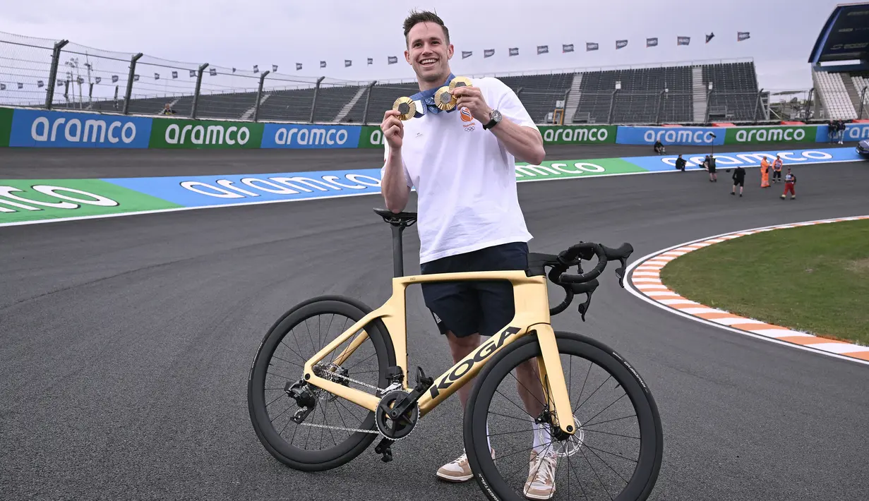 Atlet balap sepeda track Belanda, Harrie Lavreysen berfoto dengan tiga medali emas Olimpiade Paris 2024 saat bersepeda bareng pembalap Ferrari, Charles Leclerc menjelang Formula 1 GP Belanda di Sirkuit Zandvoort, Kamis (22/08/2024) waktu setempat. (AFP/John Thys)