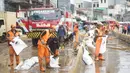 Petugas Penanganan Prasaran dan Sarana Umum (PPSU) membersihkan lumpur yang mengendap di sepanjang Jalan Jatinegara Barat, Kampung Melayu, Jakarta Timur, Kamis (2/1/2020). Petugas melakukan bersih-bersih menyusul mulai surutnya banjir di kawasan tersebut. (Liputan6.com/Immanuel Antonius)