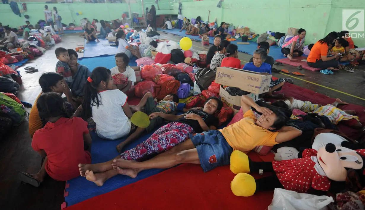 Warga beristirahat di lokasi pengungsian di GOR Suweca, Klungkung, Bali, Selasa (26/9). Ribuan pengungsi terus berdatangan menyusul peningkatan frekuensi gempa yang mulai dirasakan warga di kawasan Gunung Agung. (Liputan6.com/Gempur M Surya)