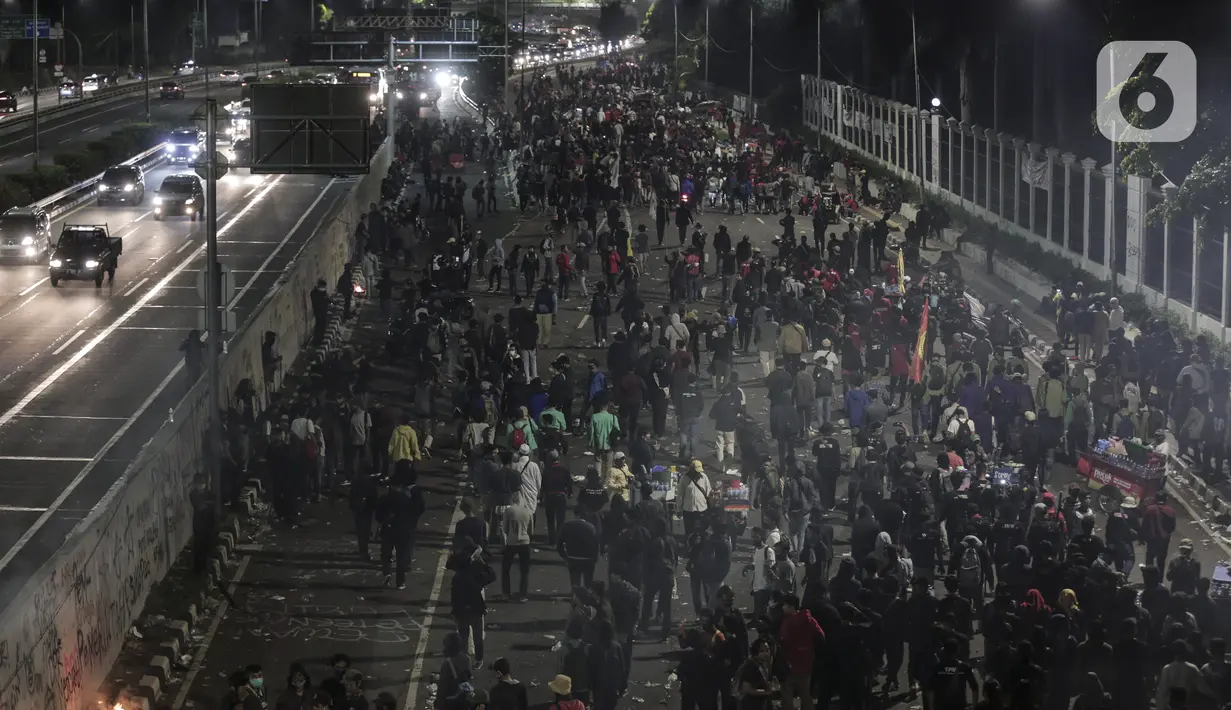 Mahasiswa dan elemen buruh bertahan hingga malam saat aksi di depan Gedung DPR/MPR/DPD, Jakarta, Kamis (16/7/2020). Dalam aksinya, mereka menolak pengesahan RUU Cipta Kerja atau Omnibus Law yang saat ini sedang dibahas DPR bersama pemerintah. (Liputan6.com/Johan Tallo)