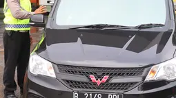 Petugas memeriksa kelengkapan administrasi pengendara saat penyekatan larangan mudik lebaran di gerbang tol Cikupa, Kabupaten Tangerang, Banten, Kamis (6/5/2021). Penyekatan dilakukan seiring telah diberlakukan larangan mudik Lebaran mulai dari 6 hingga 17 Mei 2021.  (Liputan6.com/Angga Yuniar)