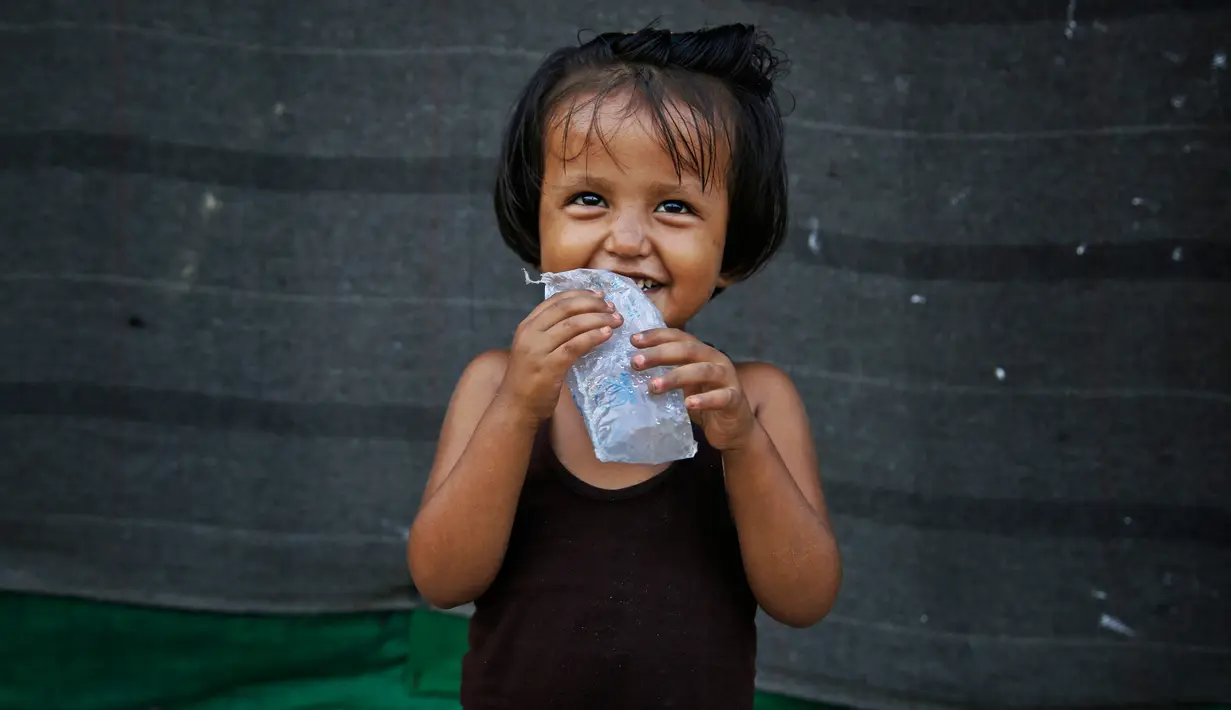 Seorang gadis pengungsi Rohingya tersenyum saat bermain di luar gubuknya di kamp pengungsi di New Delhi, India (12/9). Kekerasan yang dialami ratusan ribu warga Rohingya di Myanmar membuat mereka berlindung ke negara terdekat. (AP Photo/Altaf Qadri)