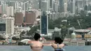 Wisatawan melihat pemandangan kota yang memukau dari kolam renang atap hotel Marina Bay Sands. Singapura dinobatkan sebagai kota paling mahal di dunia untuk tiga tahun berturut-turut di atas Zurich, Hong Kong, Jenewa dan Paris. (AFP PHOTO/Roslan RAHMAN)