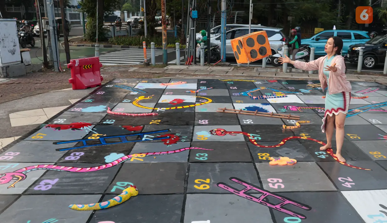 Pengunjung bermain ular tangga pada pameran seni rupa kontemporer luar ruang Jakarta Provoke! di Taman Menteng, Jakarta Pusat, Jumat (17/7/2026). Pameran gratis yang berlangsung hingga 26 Juli 2026 ini menghadirkan 25 karya dari 25 seniman dan kolektif tentang dinamika kehidupan Jakarta. (KLY/Budy Santoso)