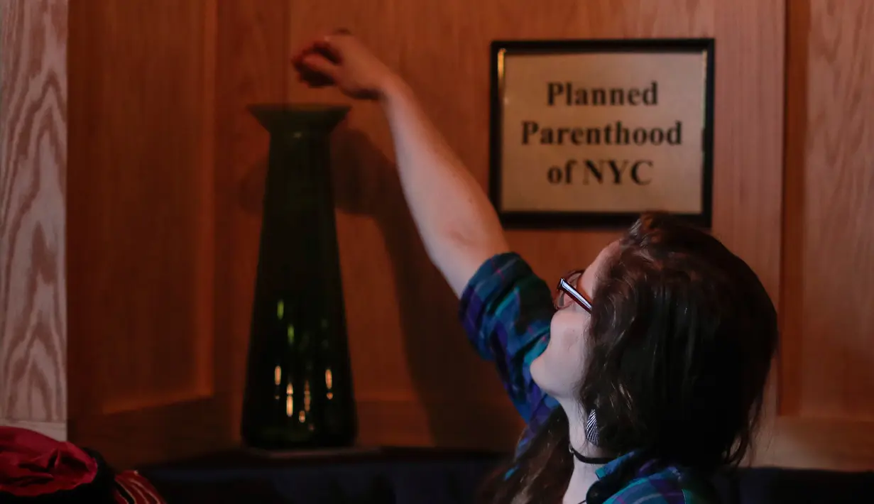 Seorang pelanggan memasukan token saat mengunjungi bar anti-Trump di New York City (25/4). Pemilik bar mengatakan bahwa mereka akan memberikan 100 persen keuntungan mereka kepada kelompok, berdasarkan jumlah token terbanyak. (AP Photo/Julie Jacobson)