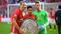 Kiper Manchester United, David de Gea (kanan), Jesse Lingard (tengah), dan Zlatan Ibrahimovic berfoto bersama dengan trofi Community Shield setelah memenangkan laga saat melawan Leicester City di Stadion Wembley, London, 7 Augustus 2016. Kiper berkebangsaan Spanyol tersebut berhasil mempersembahkan tiga trofi Community Shield saat membela Setan Merah, yaitu pada 2011, 2013, dan 2016. (AFP/Glyn Kirk)