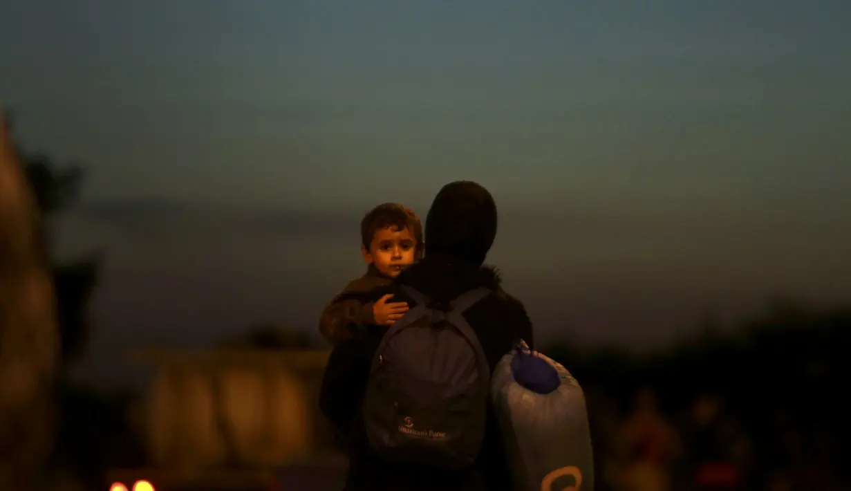 Seorang migran membawa anaknya setelah melintasi perbatasan Austria-Hungaria ke Nickelsdorf, Austria (21/9/2015). Diperkirakan sekitar 10.700 migran telah masuk ke Austria dari Hongaria pada hari Minggu (20/9) (REUTERS / David W Cerny)