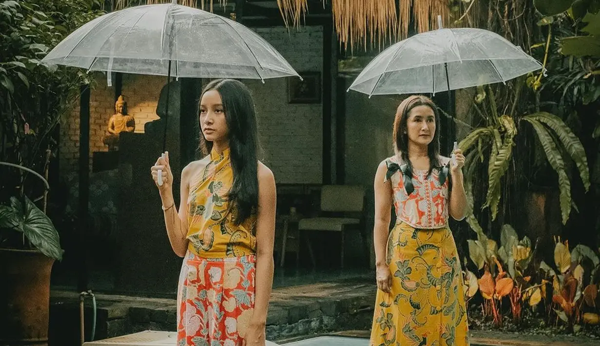 Tampil kompak dengan rambut yang dibiarkan tergerai, Widi dan Widuri tampil menawan dengan hasil foto yang estetik. Apalagi dengan latar belakang tumbuhan hijau dan bangunan vintage. Payung yang dipegang masing-masing juga membuat pemotretan bertema hujan itu terlihat begitu syahdu. (Liputan6.com/IG/@widimulia)