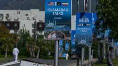 Para pekerja berjalan melewati papan reklame di dekat Hotel Serena, menjelang putaran kedua negosiasi antara Amerika Serikat dan Iran, di Islamabad, Pakistan, Senin 20 April 2026. Hari ini, Senin 20 April 2026, Iran secara resmi menyatakan menolak mengirimkan delegasi untuk melanjutkan perundingan damai tahap dua dengan Amerika Serikat (AS) di Islamabad, Pakistan. (AP Photo/Anjum Naveed)