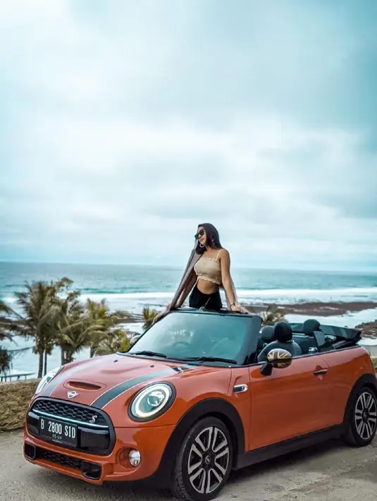 Anya Geraldine selalu tampil memukau di setiap gaya penampilannya. Seperti saat ia bersantai di pantai dengan menaiki mobil atap terbuka. Gaya kecenya berdiri menikmati sejuknya angin pantai ini menyita perhatian netizen. (Liputan6.com/IG/@anyageraldine)