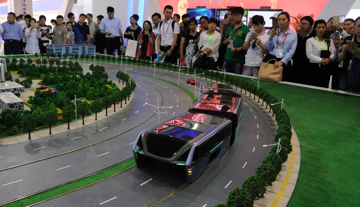 Pengunjung melihat sebuah model bus yang mengangkangi jalan di sebuah pameran di Beijing, Cina, (19/5). Bus ini bergerak menggunakan listrik, lebih hemat energi karena membawa 1.200 orang setara 40 bus konvensional. (REUTERS/Hu Qingming)