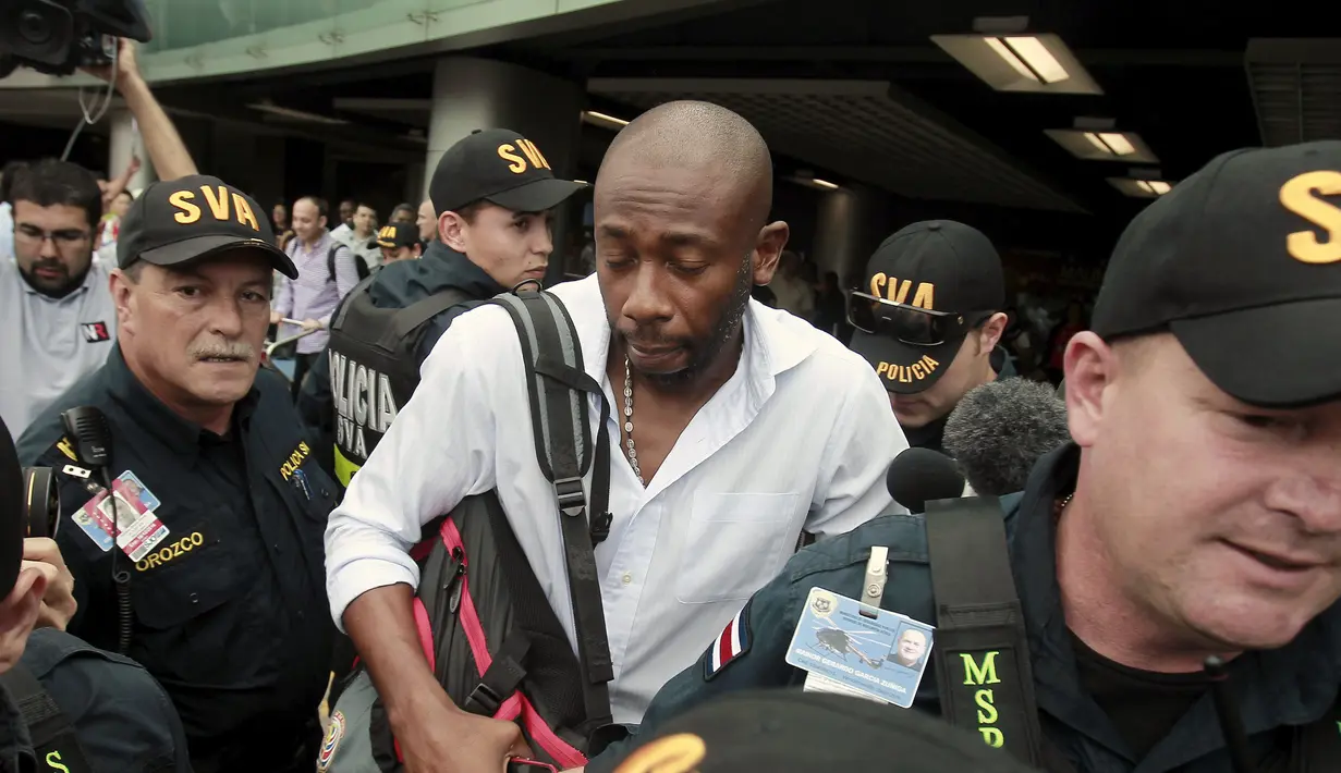 Pelatih timnas Kosta Rika, Paulo Wanchope (tengah) dikawal polisi saat tiba di bandara internasional Juan Santamaria, Alajuela 12 Agustus 2015. Wanchope terlibat dalam perkelahian saat kualifikasi Olimpiade melawan Panama. (REUTERS/Juan Carlos Ulate)