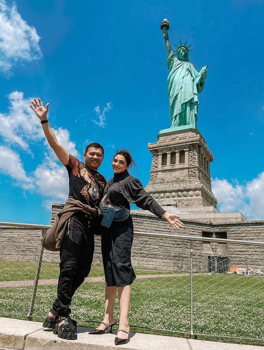 Anang Hermansyah saat berpose bersama istrinya Ashanty berpose di bawah Patung Liberty. Keduanya kompak mengenakan outfit serba hitam. (Instagram/ashanty_ash)
