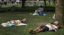 Sejumlah warga beristirahat di tempat teduh saat siang hari yang panas di Washington Square Park di New York City (17/7/2019). Gelombang panas besar akan mempengaruhi hampir dua pertiga dari Amerika Serikat, dengan Pantai Timur dan Midwest. (AFP Photo/Drew Angerer)