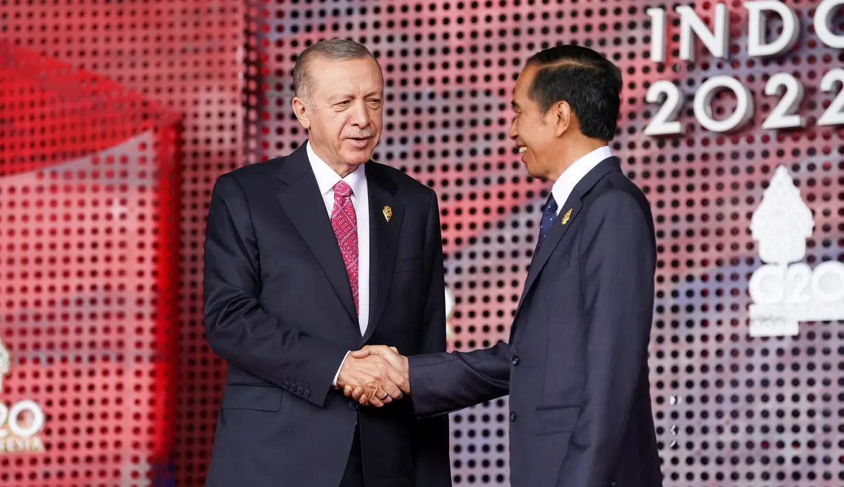 Presiden Turki Recep Tayyip Erdogan (kiri) berjabat tangan dengan Presiden Indonesia Joko Widodo  atau Jokowi yang menyambutnya pada hari pertama Konferensi Tingkat Tinggi (KTT) G20 di Nusa Dua, Bali, Selasa (15/11/2022) pagi. Selain bersalaman, Jokowi dan para pemimpin itu melakukan sesi foto bersama. (KEVIN LAMARQUE / POOL / AFP)