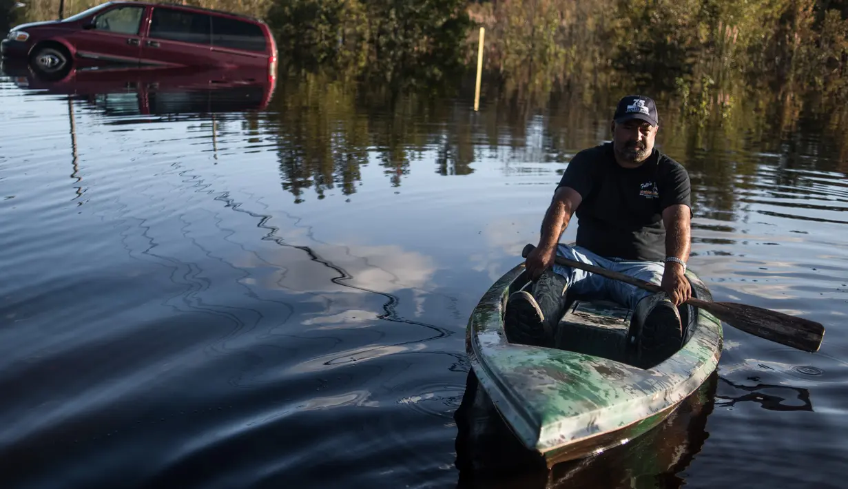 Eric Locklear melintasi banjir menggunakan kano di wilayah Lumberton, Carolina Utara, AS, 12 Oktober 2016. Banjir akibat badai Matthew tersebut merendam kota berpenduduk 21.000 orang itu. (Sean Rayford/Getty Images/AFP)