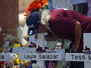 Seorang pria mencium salib Layla Salazar dalam sebuah peringatan di luar Robb Elementary School untuk menghormati para korban yang tewas dalam penembakan di sekolah awal pekan ini, Uvalde, Texas, Amerika Serikat, 28 Mei 2022. (AP Photo/Dario Lopez-Mills)