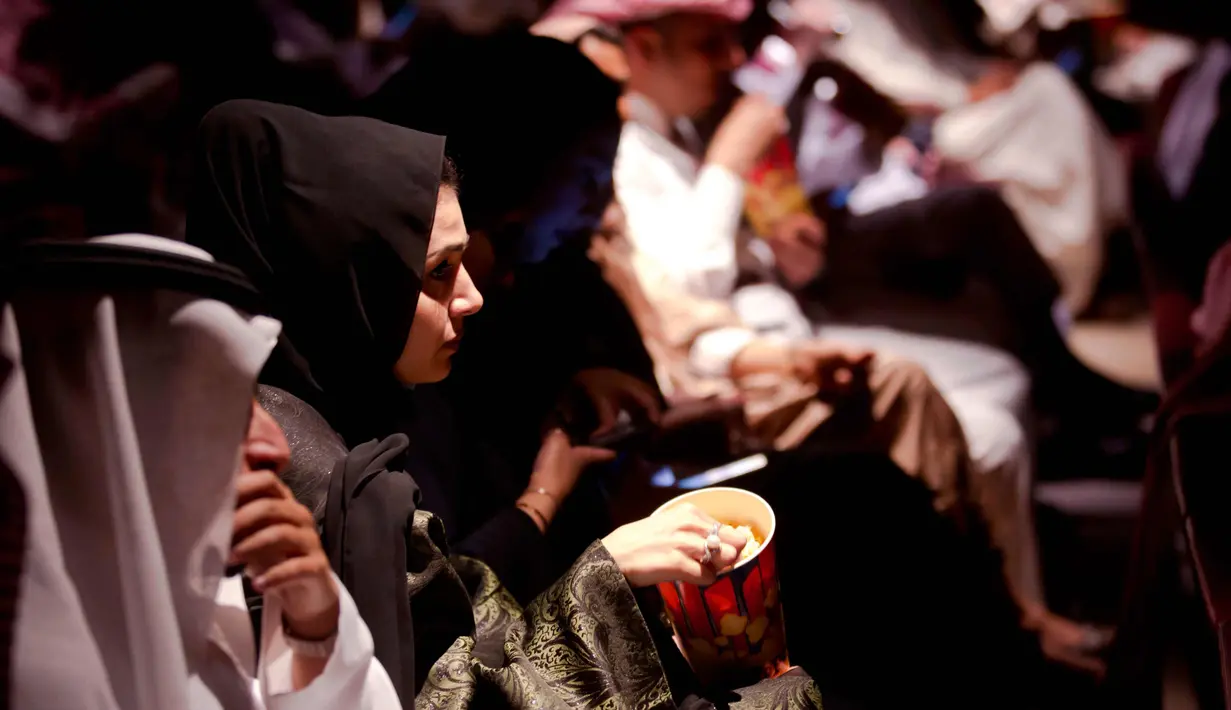 Seorang pengunjung perempuan memakan popcorn saat bersiap menyaksikan film Black Panther selama acara gala undangan di King Abdullah Financial District Theatre, Riyadh, Arab Saudi (18/4). (AP/Amr Nabil)