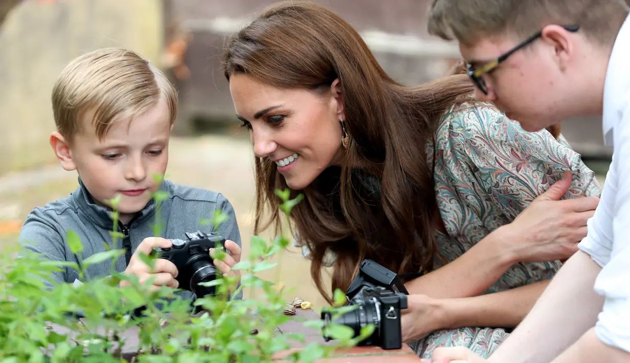 Duchess of Cambridge Kate Middleton melihat hasil foto seorang anak saat ikut serta belajar fotografi dengan Action for Children di Kingston upon Thames, Inggris (25/6/2019). (AFP Photo/Chris Jackson)