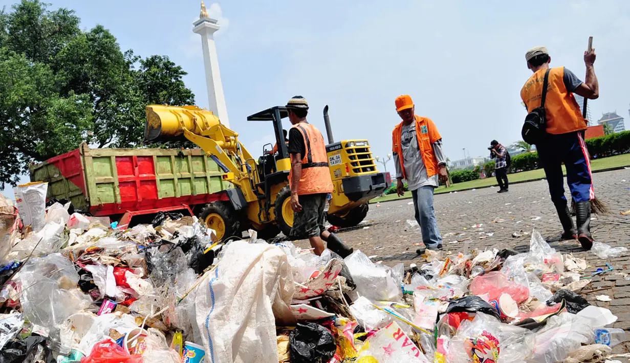 Petugas kebersihan dari dinas kebersihan Pemprov DKI Jakarta bekerja ekstra untuk membersihkan sampah di  kawasan Monumen Nasional, Jakarta, (31/7/2014). (Liputan6.com/Faizal Fanani)
