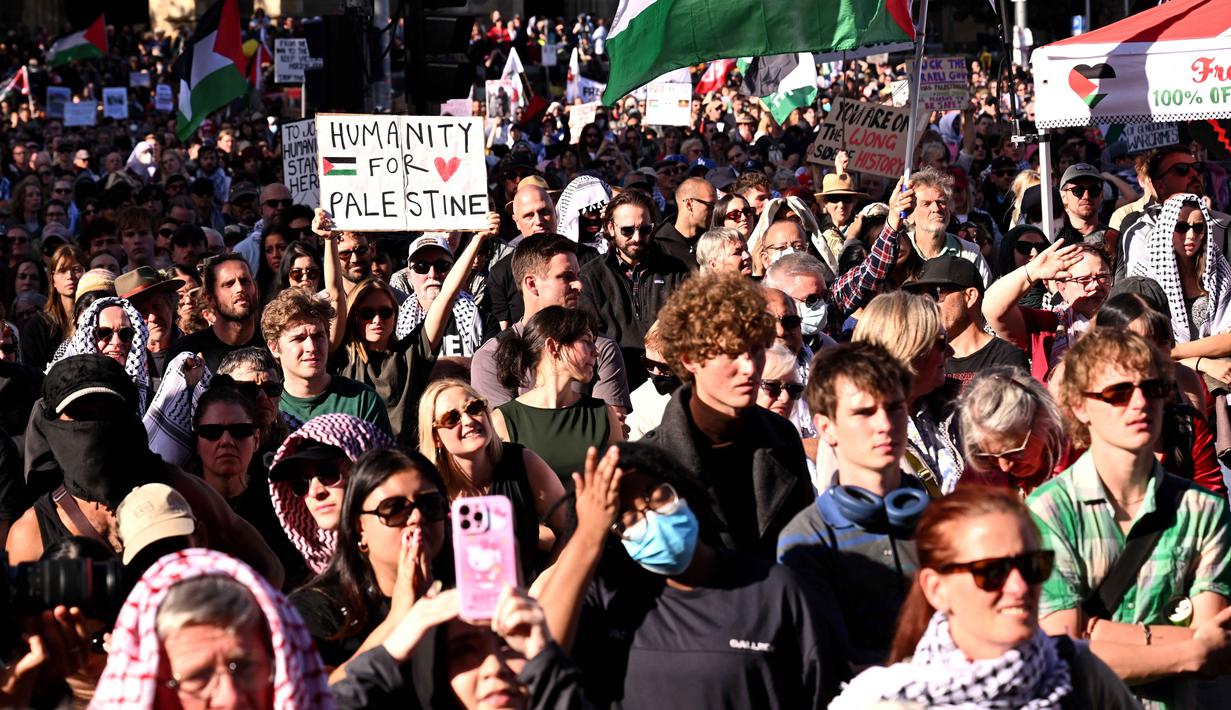 Unjuk rasa ini bertepatan dengan kunjungan Presiden Israel, Isaac Herzog, ke kota tersebut. Tampak dalam foto, para pengunjuk rasa memegang plakat dan bendera di luar stasiun Flinders Street selama kunjungan Presiden Israel, Isaac Herzog, di Melbourne, Australia, pada Kamis 12 Februari 2026. (WILLIAM WEST/AFP)