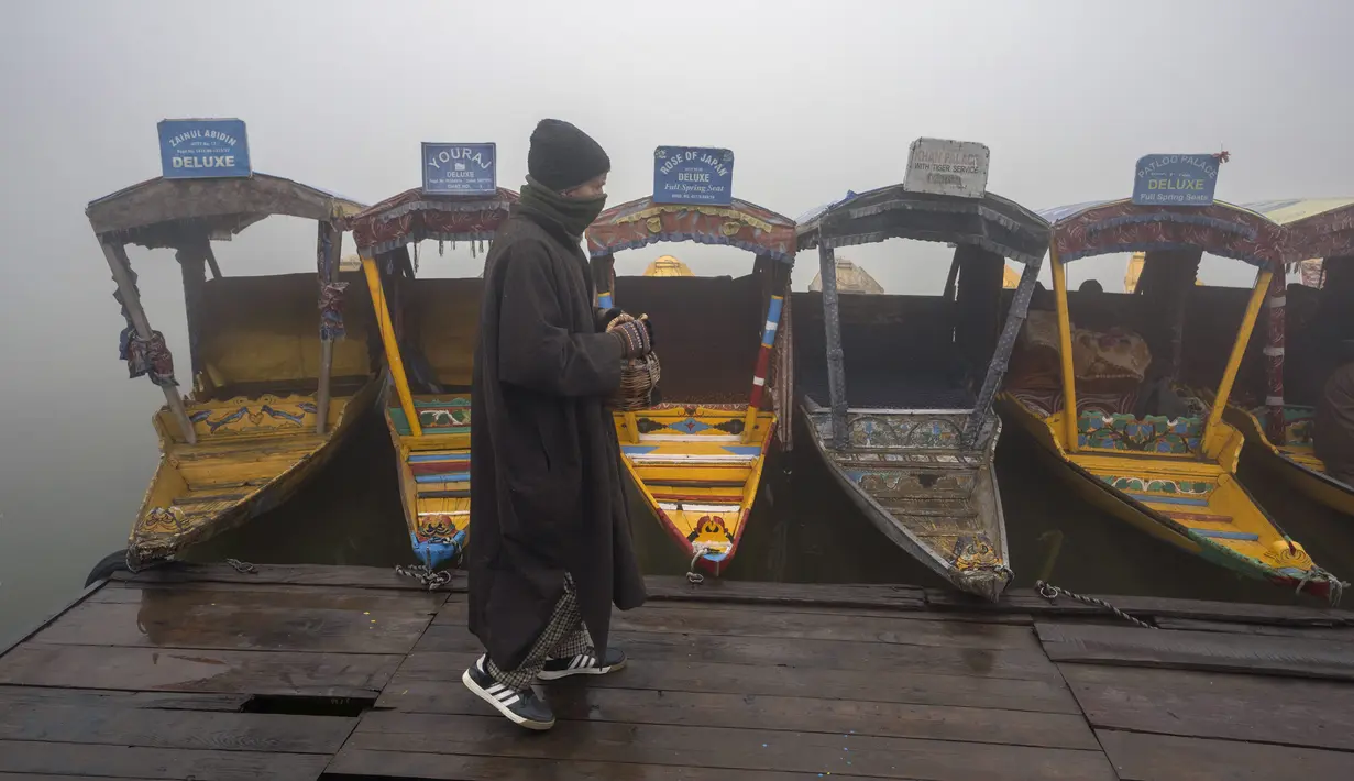 Warga Kashmir melintasi Danau Dal dengan perahu di bawah kabut tebal pada pagi yang dingin di Srinagar, Kashmir yang dikuasai India, Jumat, 29 Desember 2023. (AP Photo/Dar Yasin)